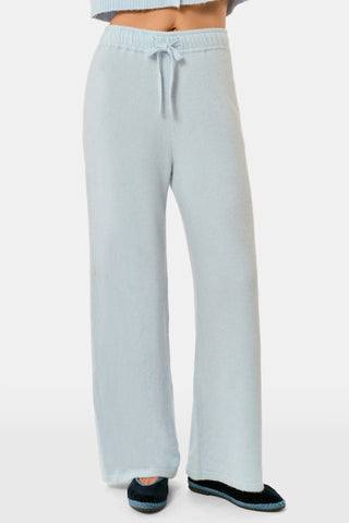 A woman poses with her arms crossed, wearing an icy blue AFFINA Moxie Cardigan with pearl-like buttons and matching drawstring pants.