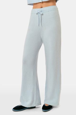 A woman poses with her arms crossed, wearing an icy blue AFFINA Moxie Cardigan with pearl-like buttons and matching drawstring pants.