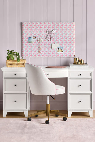 White desk with chair, pink decorative wall panel, and small plant in a room with light purple walls.