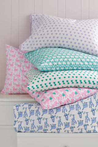 Stack of patterned pillows on a white dresser with a window in the background