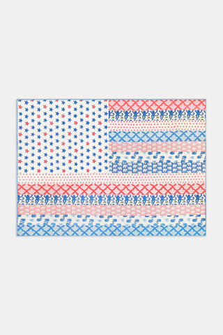 The Liberty Stripe Quilted Flag by JEFF AKSEIZER features a stylized patchwork American flag design, with patterned rows of stars, Xs, and repeating Democratic donkey and Republican elephant icons in red and blue on a white background, reminiscent of Roller Rabbit fabrics.