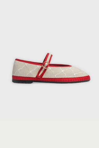 The Jena Embroidery Pierre by FLABELUS is a beige linen Mary Jane shoe with white embroidery, red trim and strap, gold button, and red sole. Made in Spain. Displayed on a plain white background.
