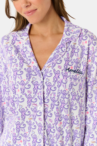 A woman smiles while wearing the TEXPIMA Get Ready With Me Blake Robe, featuring a knee-length cut and a purple and pink paisley pattern, tied at the waist, against a plain white background.