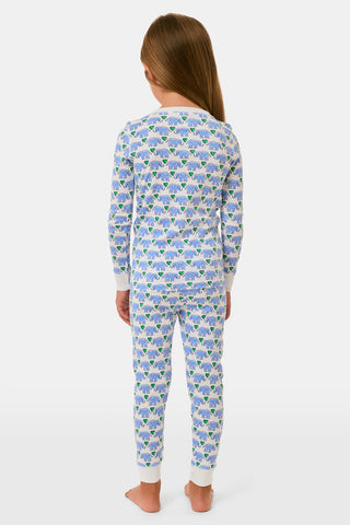 A young girl smiles in Roller Rabbit Kids Hathi Hearts Pajamas with long sleeves and a colorful animal print. She has long brown hair, is barefoot, and stands against a plain white background.
