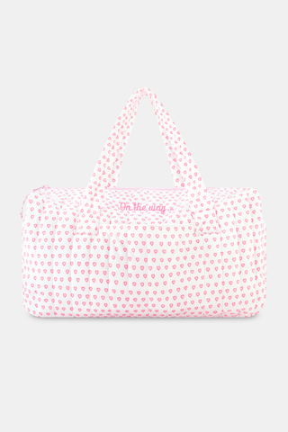 The Roller Rabbit Hearts Quilted Weekender is a rectangular pink and white travel bag with two handles, showcasing a pink heart pattern on quilted nylon, set against a plain light gray background.