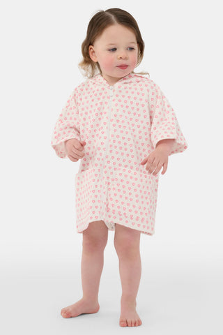 A young girl with long brown hair wears the Roller Rabbit Kids Hearts Jesse Cover Up, a white hooded zip-up towel robe with pink hearts and front pockets, smiling at the camera against a plain light background.