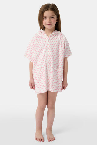 A young girl with long brown hair wears the Roller Rabbit Kids Hearts Jesse Cover Up, a white hooded zip-up towel robe with pink hearts and front pockets, smiling at the camera against a plain light background.