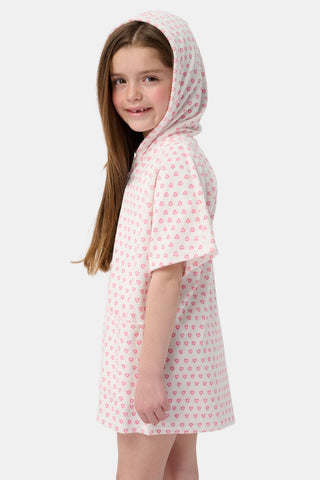A young girl with long brown hair wears the Roller Rabbit Kids Hearts Jesse Cover Up, a white hooded zip-up towel robe with pink hearts and front pockets, smiling at the camera against a plain light background.