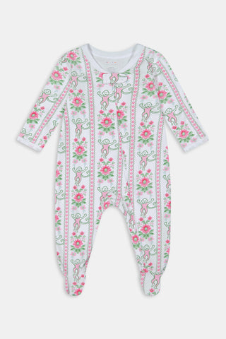 A light-skinned, dark-haired baby sits outdoors on a blue and white blanket, wearing Roller Rabbit Infant Monkey Block Stripe Zipper Footie, with green grass and bushes in the background.