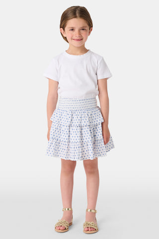 A child wears a white short-sleeved top and the Roller Rabbit Kids Hearts Sami Skirt, featuring three ruffled layers and playful blue heart patterns. The background is plain white.