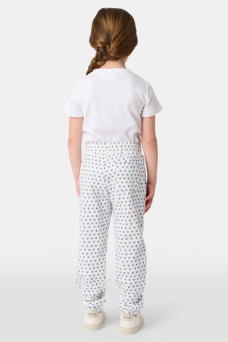 A young child smiles while wearing Roller Rabbit Kids Hearts Sweatpants and a plain white t-shirt, with one hand in the pocket and looking slightly to the side.