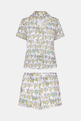 The Kappa Alpha Theta Monkey Polo Pajamas from Roller Rabbit are a short-sleeve button-up set with matching shorts, showcasing a lively print of colorful cartoon monkeys and doodles on a crisp white background. They feature an elastic waistband for comfort and are crafted from soft Pima cotton for a gentle feel.