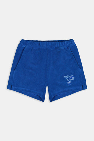 A child wears the Roller Rabbit Kids Monkey Embroidery Hanni Short, navy terry shorts with a monkey embroidered on the left leg, paired with a matching blue top and white velcro sneakers against a plain white background.
