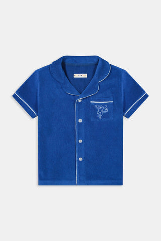 The Roller Rabbit Kids Monkey Embroidery Leo Polo is a royal blue, short-sleeved terry shirt with white piping, a notched collar, and an embroidered monkey on the chest pocket.