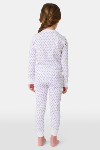 A young child with brown hair smiles barefoot, wearing the Roller Rabbit Kids Hearts Pajamas set with long sleeves and pants against a plain white background.