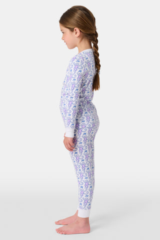 A young child stands smiling in Roller Rabbit Kids Monkey Pajamas, featuring soft Pima cotton, a playful monkey print, white cuffs, and a buttoned neckline, against a plain white background.