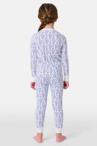 A young child stands smiling in Roller Rabbit Kids Monkey Pajamas, featuring soft Pima cotton, a playful monkey print, white cuffs, and a buttoned neckline, against a plain white background.