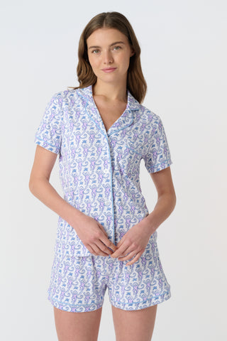 A close-up of Monkey Polo Pajamas made from pima cotton, featuring playful blue and pink monkeys holding branches on a white background—a cozy choice for a polo-style pajama set.