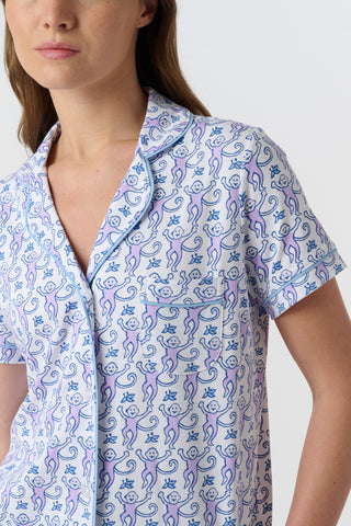A close-up of Monkey Polo Pajamas made from pima cotton, featuring playful blue and pink monkeys holding branches on a white background—a cozy choice for a polo-style pajama set.