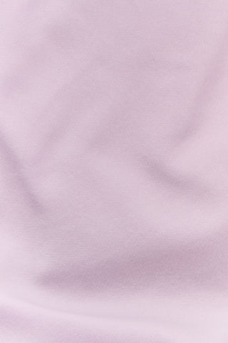 A woman wearing the Roller Rabbit Sleep Club Andie Sweatshirt in pastel lavender, paired with patterned white shorts, stands and smiles against a plain white background.