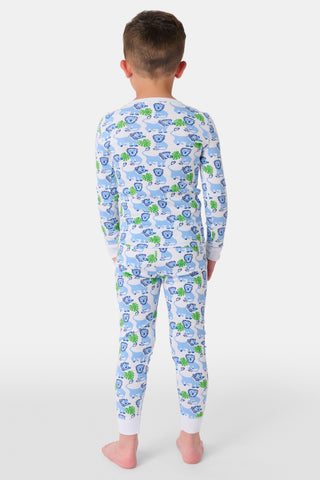 A young child with curly hair smiles barefoot against a plain white background while wearing Kids Leo The Lion Pajamas, crafted from soft Pima cotton.