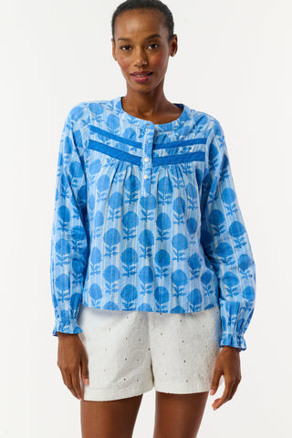 Woman wearing a blue floral blouse and white shorts on a white background