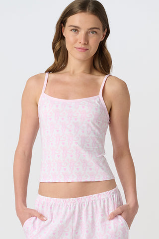 Woman with long brown hair wears a Roller Rabbit Lovely Monkey Clarkson Cami with adjustable straps and matching pajama pants, hands in pockets, standing against a plain light background.
