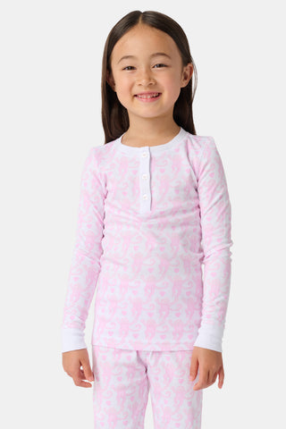 A child stands barefoot, smiling in Kids Lovely Monkey Pajamas with a playful monkey print and a buttoned neckline, set against a plain white background.