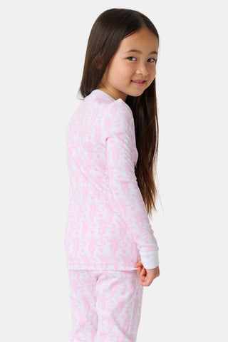 A child stands barefoot, smiling in Kids Lovely Monkey Pajamas with a playful monkey print and a buttoned neckline, set against a plain white background.