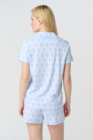 Lovely Monkey Polo Pajamas feature a light blue cartoon monkey pattern with heart-shaped tails and small blue hearts on a white background, adding cheerful charm and whimsy to any Pima cotton pajamas collection—perfect for weddings.