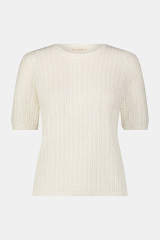 A woman wearing the Roller Rabbit Chain Pointelle Lauren Sweater in cream and white pants, standing against a white background.