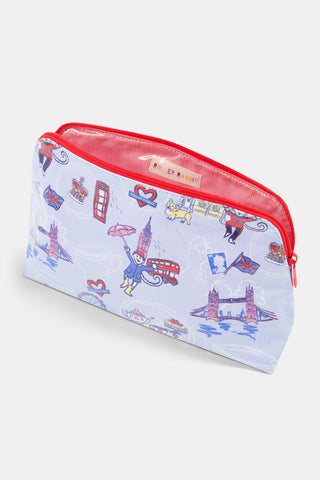 Introducing the London Monkey Makeup Bag by Roller Rabbit—a rectangular cotton canvas pouch with a light blue background, decorated with playful illustrations including Big Ben, Tower Bridge, a red double-decker bus, a crown, a teacup, and the signature monkey character holding an umbrella. Finished with a vibrant red zipper.