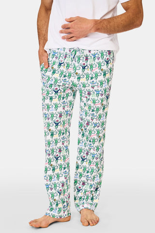 A person wears Mens Boston Monkey Simon Pant, featuring a colorful cartoon pickle print on soft Pima Cotton, paired with a plain white shirt and standing barefoot with one hand in their pocket.