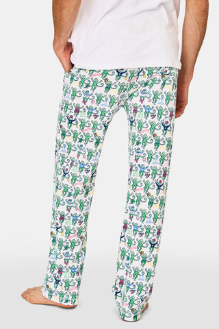 A person wears Mens Boston Monkey Simon Pant—white Pima cotton pajama pants with a colorful monkey print—standing barefoot and facing away, lower half visible. Perfect for cozy nights in Boston or as fun pajamas for kids.