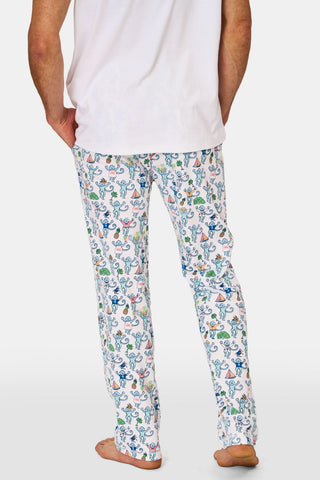 A person is wearing the Mens Charleston Monkey Simon Pant by Roller Rabbit, crafted from soft Pima cotton with a playful monkey print adorned with colorful boats and trees. Their hand rests in the pocket, and only their torso and upper legs are shown.