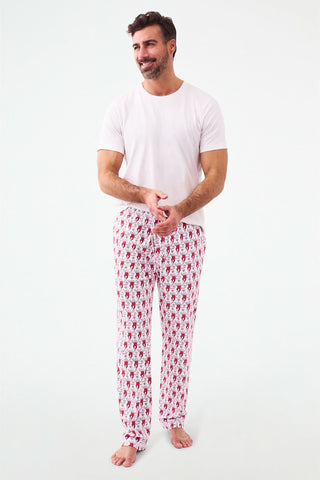 A person stands barefoot, lower half visible, wearing Roller Rabbit's Campus Mens Lovely Monkey Simon Pant—white Pima cotton pants with a red and black monkey pattern and a drawstring waist, one hand in their pocket.