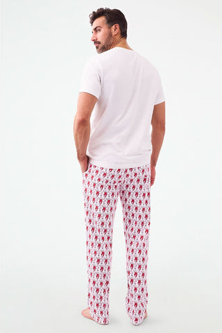 A person stands barefoot, lower half visible, wearing Roller Rabbit's Campus Mens Lovely Monkey Simon Pant—white Pima cotton pants with a red and black monkey pattern and a drawstring waist, one hand in their pocket.