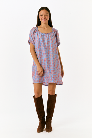 A person wearing the SAPPHIRE Mia Floral Briella Dress, a short-sleeved, blue floral babydoll mini dress with a gathered, rounded neckline and puff sleeves.