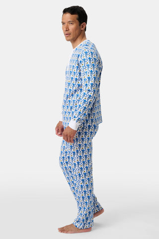 A man stands barefoot, facing sideways in Mens Monkey Spencer Pajamas—a fun, colorful monkey print set with matching long-sleeved top and pants—offering comfort and playful style against a plain light background.