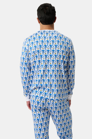 A person stands facing away, wearing Mens Monkey Spencer Pajamas featuring a blue and yellow dragon pattern on white. The plain background is also white.