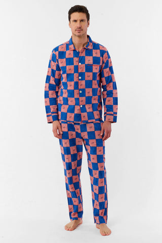 A man with short brown hair and a neutral expression stands barefoot against a white background, wearing the Roller Rabbit Mens Moby Grand Prix Loungewear set in blue and pink checkered cotton with long sleeves and pants.