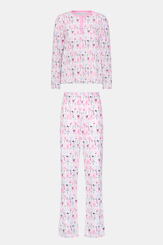 A woman with long brown hair stands next to white lockers, looking at the camera and holding a box, wearing Roller Rabbit's Monkey Pirouette Pajamas featuring a pink-patterned dancing monkey print in soft Pima cotton.