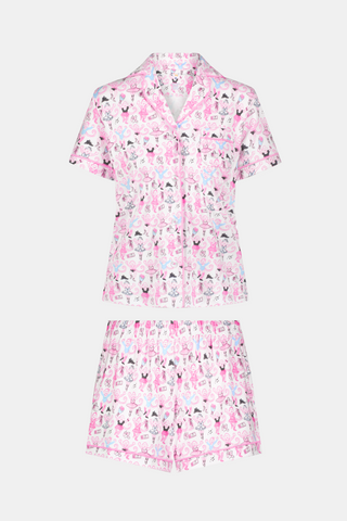 The Monkey Pirouette Polo Pajamas by Roller Rabbit feature a pink short-sleeve button-up top and matching shorts, adorned with a colorful and playful monkey, animal, and floral pattern on a white background.