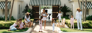 Family posing in front of a white building with green and white striped awnings.
