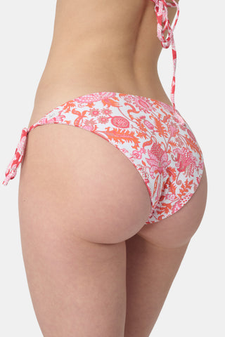 A person wears the Roller Rabbit Amanda/Jemina Serena Bikini Bottom, featuring UPF 50+ protection, white heart-shaped patterns, and side tie strings, shown from waist to mid-thigh against a plain background.
