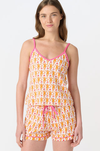 A close-up of fabric from the Monkey Mischa Set, showing a playful pattern with orange cartoon monkeys with curly tails and pink butterflies on a white background.