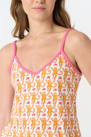 A close-up of fabric from the Monkey Mischa Set, showing a playful pattern with orange cartoon monkeys with curly tails and pink butterflies on a white background.