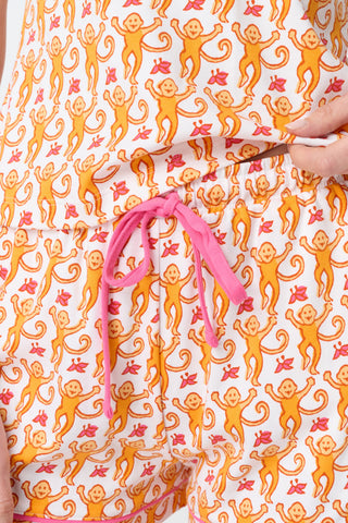A close-up of fabric from the Monkey Mischa Set, showing a playful pattern with orange cartoon monkeys with curly tails and pink butterflies on a white background.