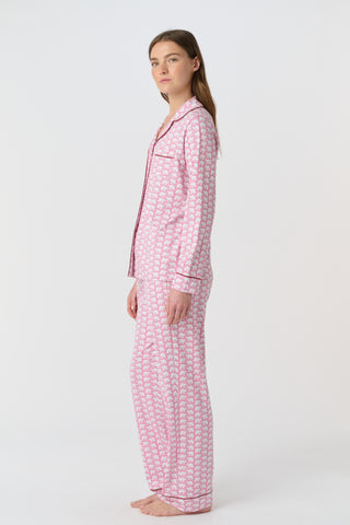 The Hathi Polo Pajamas feature white elephants outlined in red on a pink background, arranged in diagonal rows. Each stylized elephant has a red dot for an eye. Inspired by the Hathi print and made in Peru.