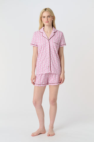 The Hathi Polo Pajamas feature white elephants outlined in red on a pink background, arranged in diagonal rows. Each stylized elephant has a red dot for an eye. Inspired by the Hathi print and made in Peru.